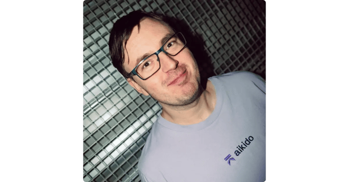 Headshot of a man with dark hair and glasses