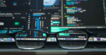 A photograph of glasses in front of a laptop