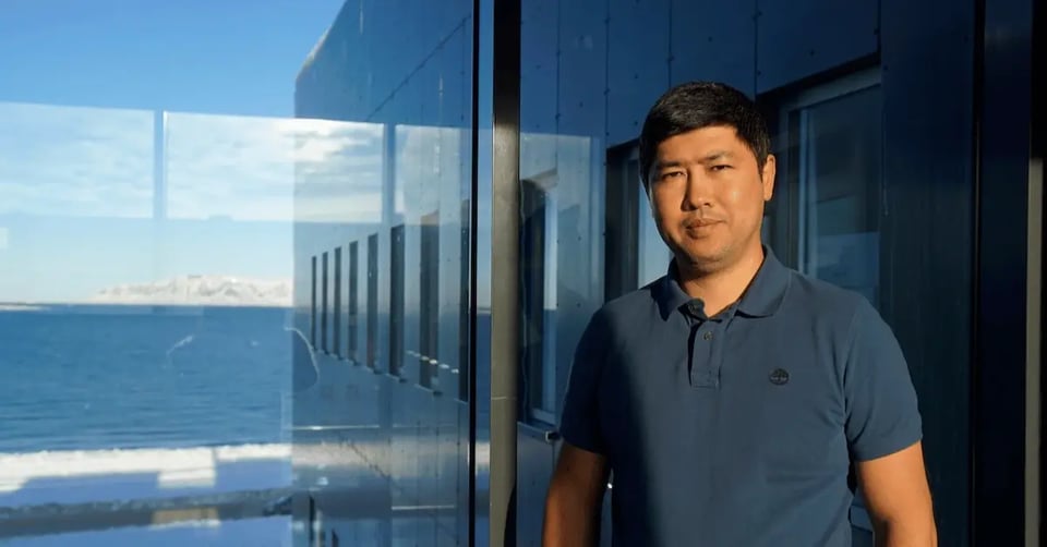 Photo of a man in an office hallway with snowy mountains outside