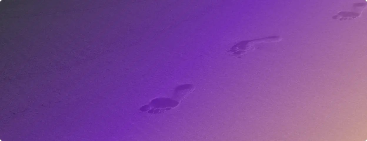 Photo of footprints in the sand with a purple filter over it.
