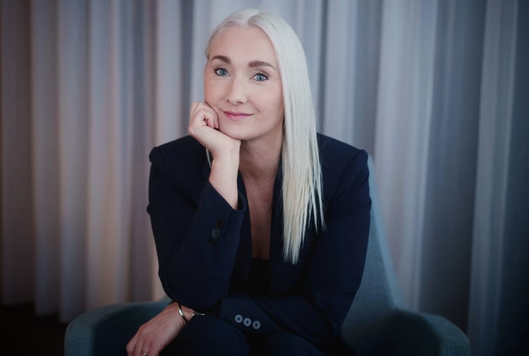 Headshot of a woman with long blonde hair in a blazer