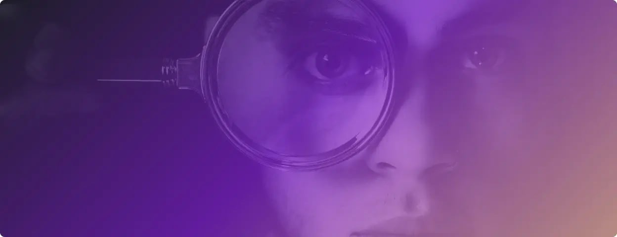 Up close photo of a man holding a magnifying glass over one eye