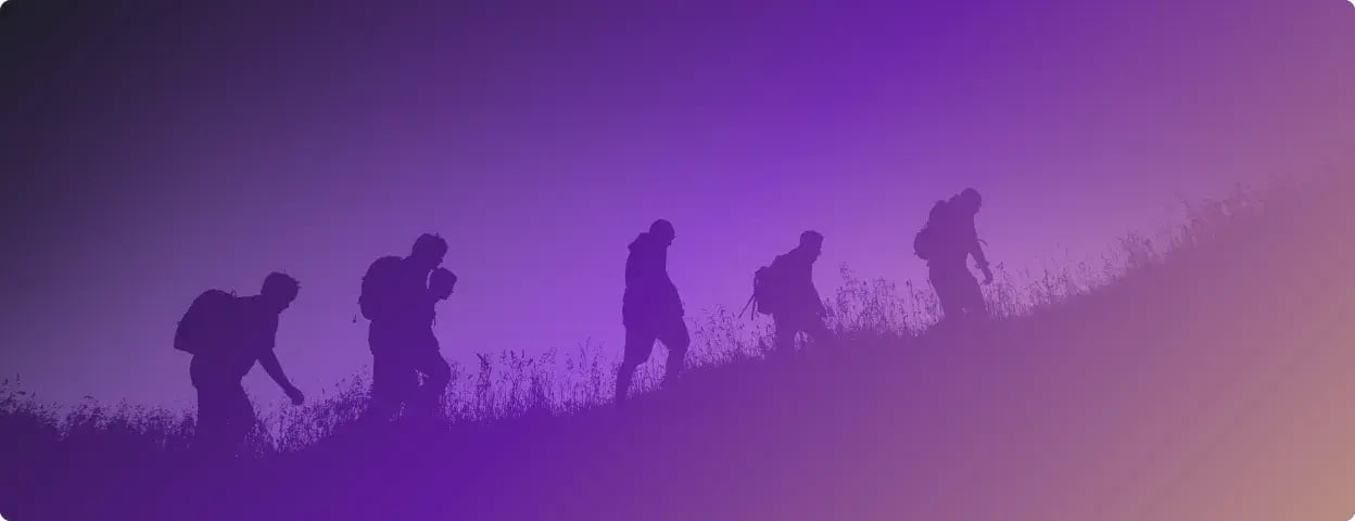 Photo of silhouettes of people walking up a grassy hill