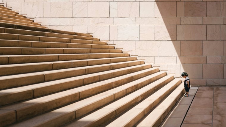 Photograph of a kid standing at the bottom of a large staircase