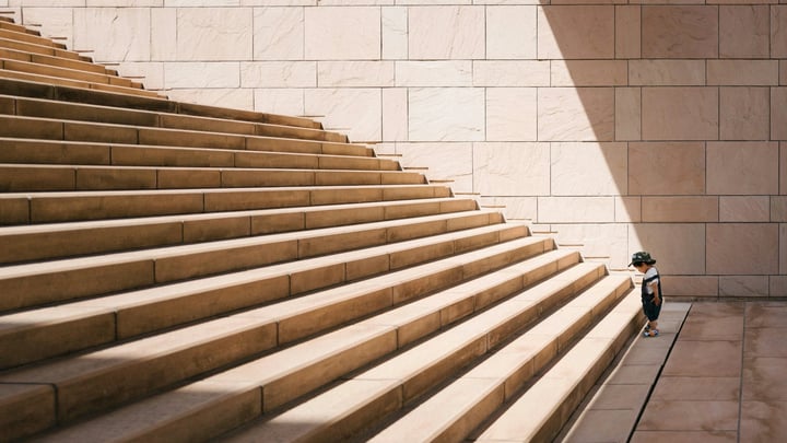Photograph of a kid standing at the bottom of a large staircase