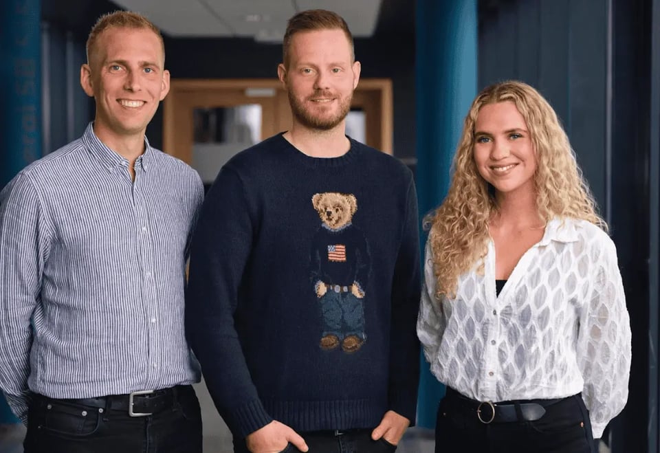 Image of 2 men and a woman standing in an office hallway