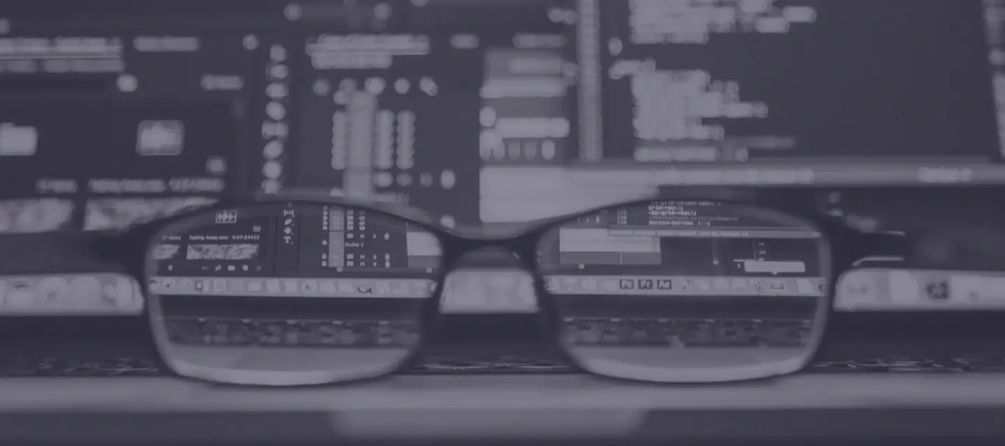 Black and white photo of glasses in front of a laptop